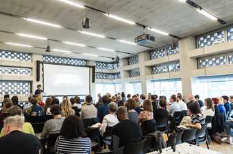 An audience listens to a presentation at Experiments in Practice, 2017