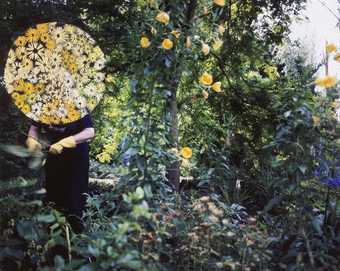 Fairbrother's mother is shown as a distant figure working in her garden, her face lost under clouds of small yellow and orange flowers, embroidered onto the original source photographs