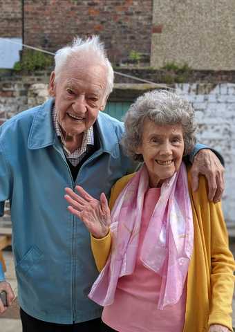  An elderly couple smile and wave at the camera 