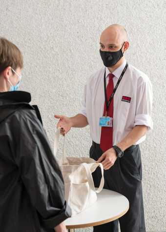 A member of security staff checking a visitors bag. 