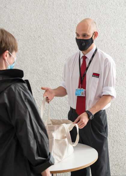 A member of security staff checking a visitors bag.