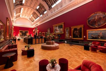 An art gallery with red walls set up for an evening event