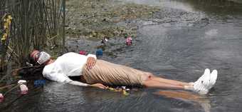 photo of a woman lying in a river with a surgical mask on