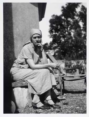 Photograph of Vanessa Bell sitting outside Charleston farmhouse, Tate Archive
