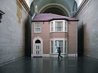Video still of spectators looking at Michael Landys installation Semi detached at Tate Britain