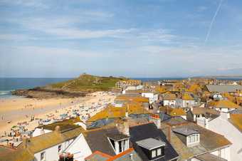 the top of the frame shows a clear blue sky. below is the bay and sea and in the foreground are yellow coloured roofs. 