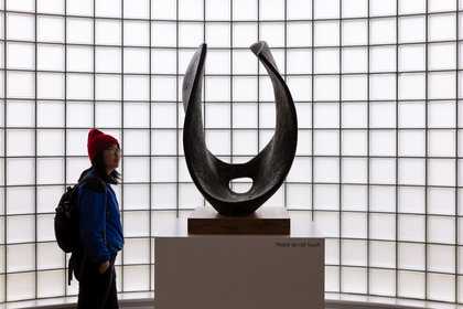 a woman looks at Dame Barbara Hepworth Curved Form (Trevalgan) sculpture in a lobby