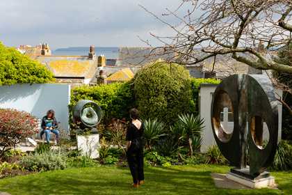 a woman stands in the Barbara Hepworth garden looking out to the view
