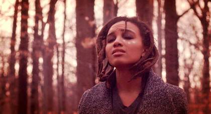 A person with their eyes closed standing in a wood