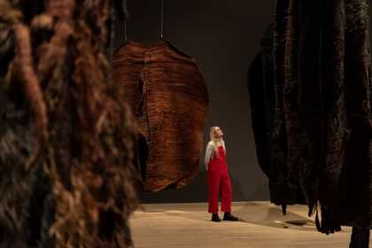 Person in red dungarees standing amongst Abakanowicz's works.