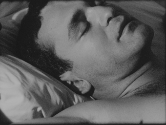 Black and white film still of a man sleeping