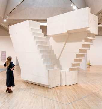 cast of some stairs in a warehouse with a woman standing in front of it