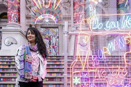 Chila Kumari Singh Burman stands in front of her artwork at Tate Britain 