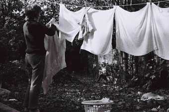 Black and white portrait photograph of a woman hanging out her washing