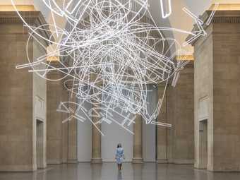 A woman stands under a light installation in the Duveens