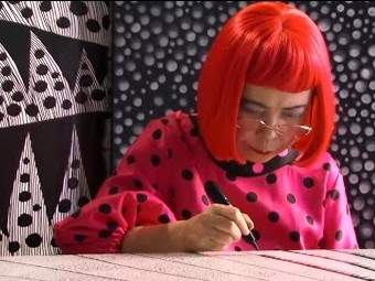 Artist Yayoi Kusama painting on a desk