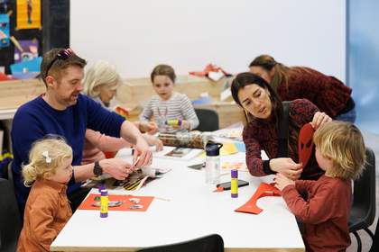 a family sits around a table making masks and playing with paper