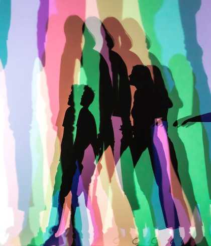 people stand in front of a rainbow shadow