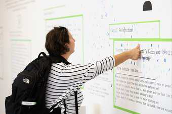 A person interacts with a display by placing their thumb print on the wall