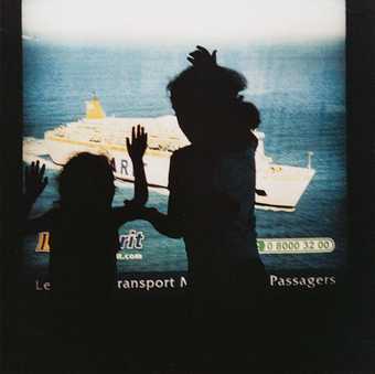Yto Barrada Advertisement lightbox Ferry port transit area Tangier  2003 photograph of a the silhouettes of two children against a poster advertisement depicting a ferry