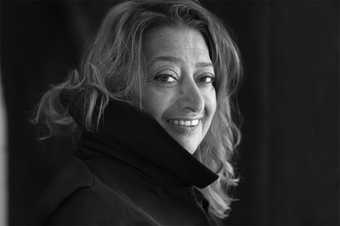 Black and white portrait of Zaha Hadid, looking over her shoulder at the camera