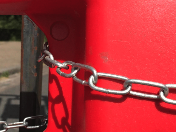 a red bollard with a metal chain across it