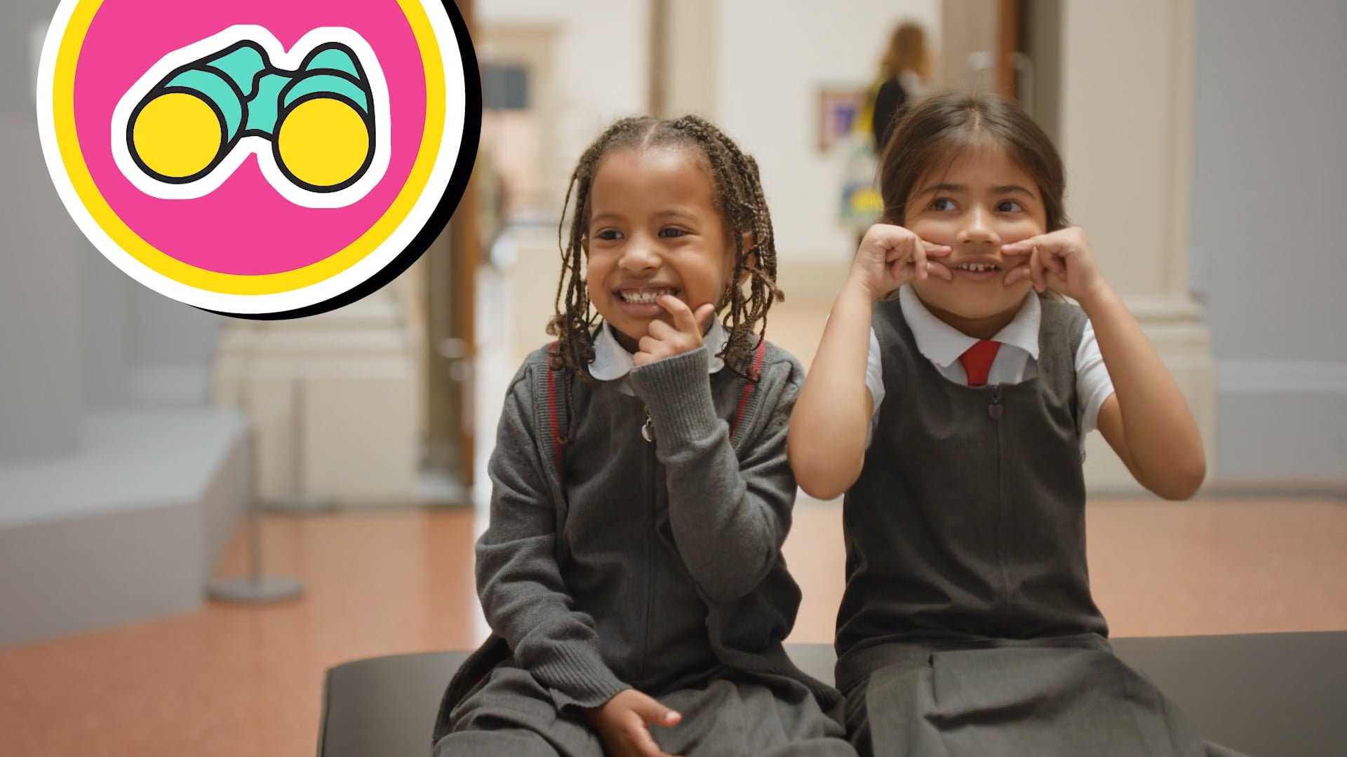 Two girls look at art in school uniform