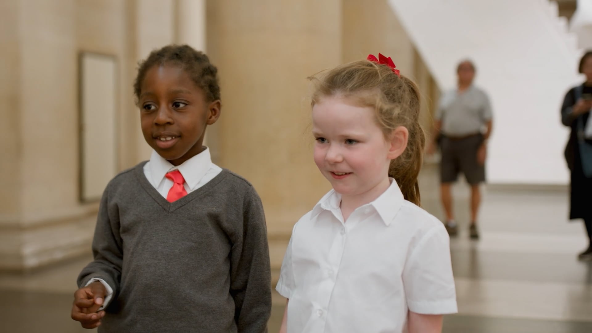 Two girls look at art in school uniform